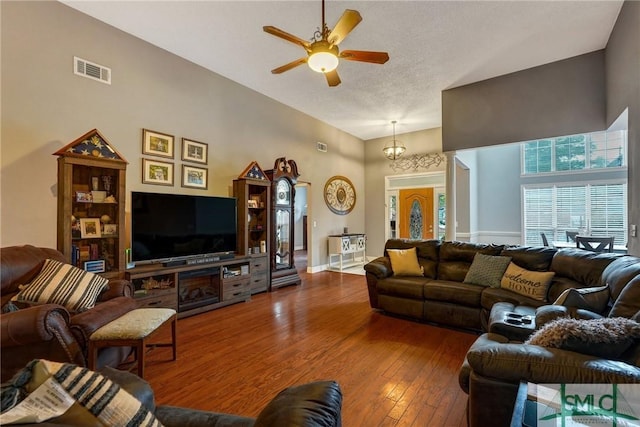 living area with ceiling fan, a textured ceiling, visible vents, baseboards, and wood-type flooring