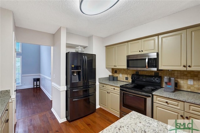 kitchen featuring backsplash, stainless steel appliances, dark wood finished floors, and cream cabinetry