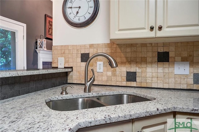 details featuring cream cabinets, backsplash, light stone counters, and a sink