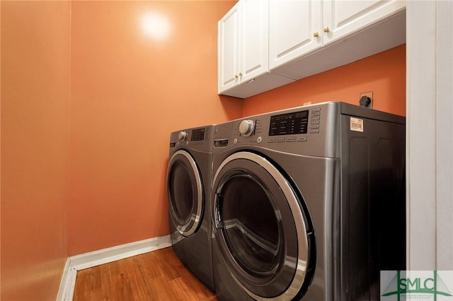 washroom featuring baseboards, cabinet space, independent washer and dryer, and wood finished floors