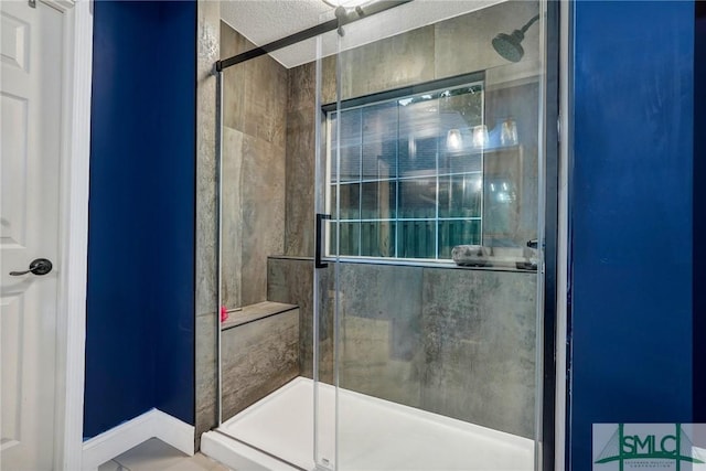full bath with a textured ceiling, baseboards, and a stall shower