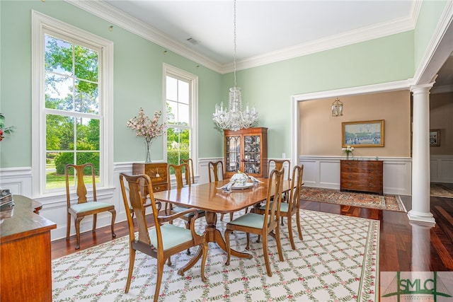 dining space with crown molding, ornate columns, wood finished floors, and a notable chandelier
