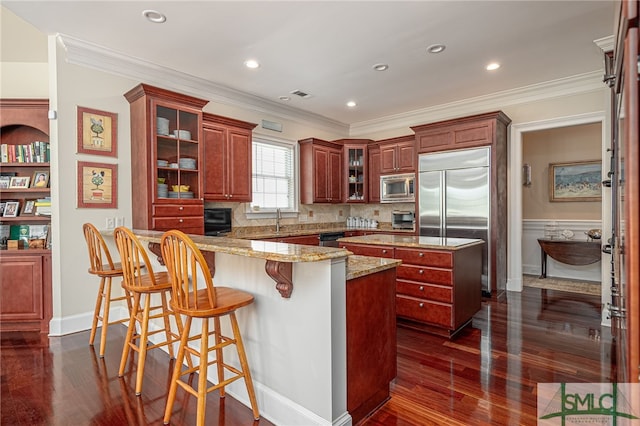 kitchen with a kitchen island, crown molding, a sink, dark wood-style floors, and built in appliances