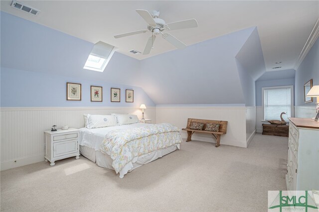 bedroom with a ceiling fan, light carpet, wainscoting, and visible vents