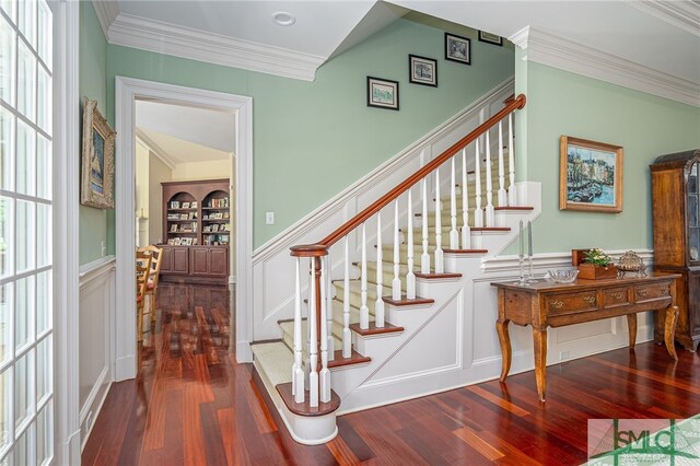 stairs with crown molding, a wainscoted wall, a decorative wall, and hardwood / wood-style floors