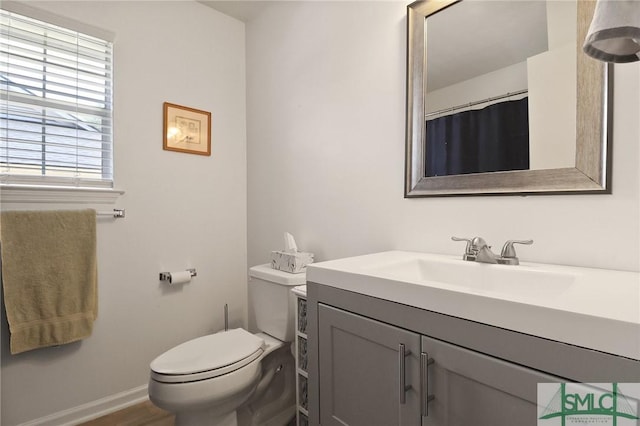 bathroom featuring toilet, baseboards, and vanity