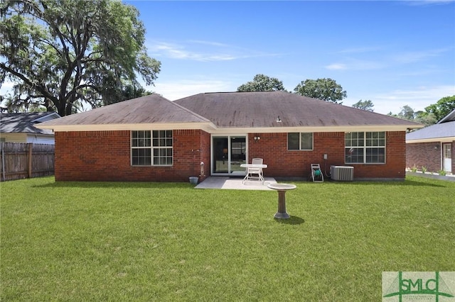 rear view of property with central air condition unit, a lawn, and a patio area