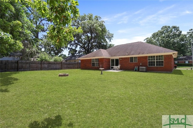 back of house with a fenced backyard, a fire pit, a yard, and central AC unit