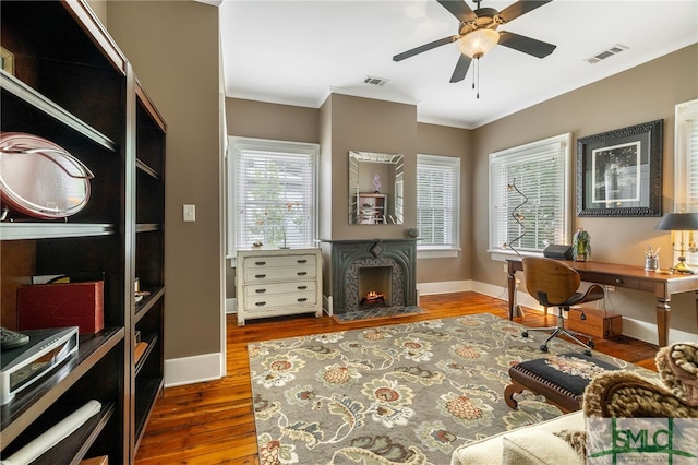 home office with baseboards, a ceiling fan, wood finished floors, and visible vents