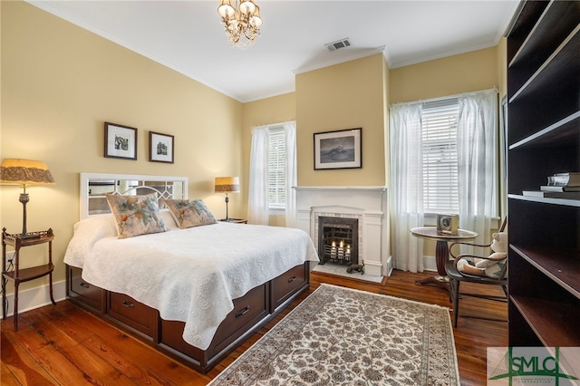 bedroom with a chandelier, visible vents, ornamental molding, and wood finished floors