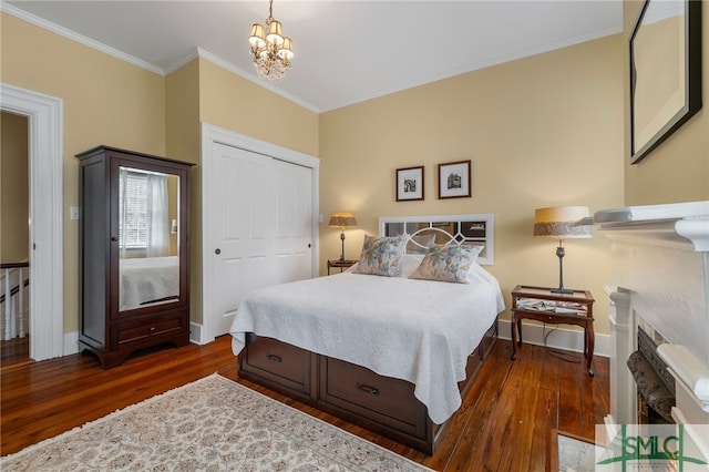 bedroom featuring crown molding, a closet, baseboards, dark wood finished floors, and a notable chandelier