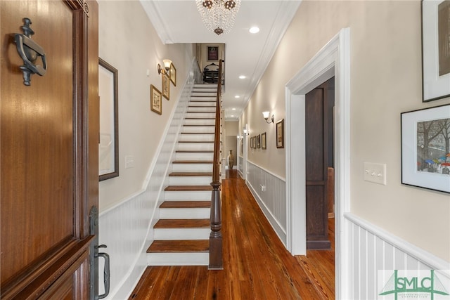 stairway featuring crown molding, wood finished floors, and a wainscoted wall
