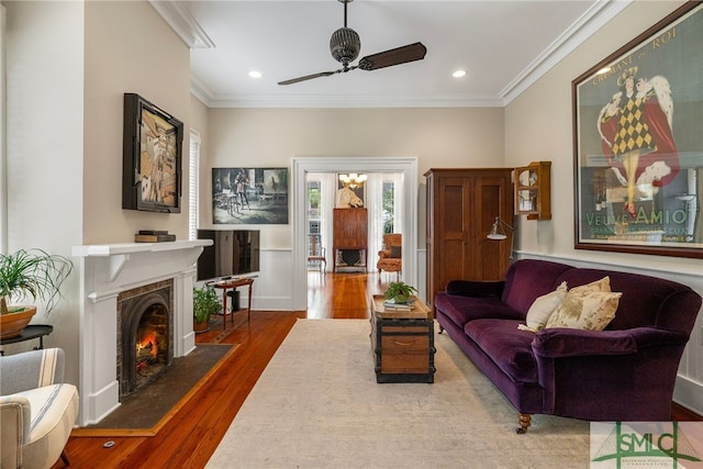 living area featuring ornamental molding, a ceiling fan, wood finished floors, recessed lighting, and a fireplace with flush hearth