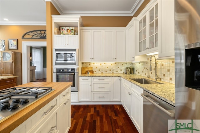 kitchen with appliances with stainless steel finishes, a sink, wood counters, dark wood-type flooring, and glass insert cabinets