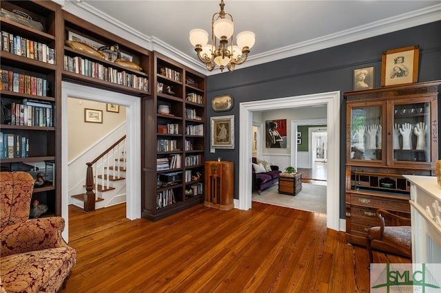 living area featuring an inviting chandelier, crown molding, dark wood-style floors, and stairway