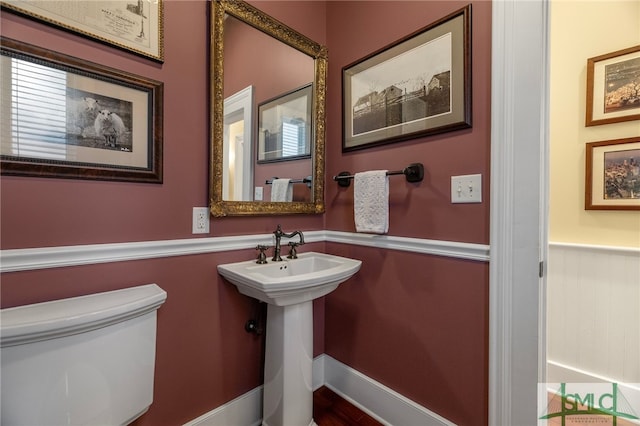 bathroom featuring toilet and a wainscoted wall