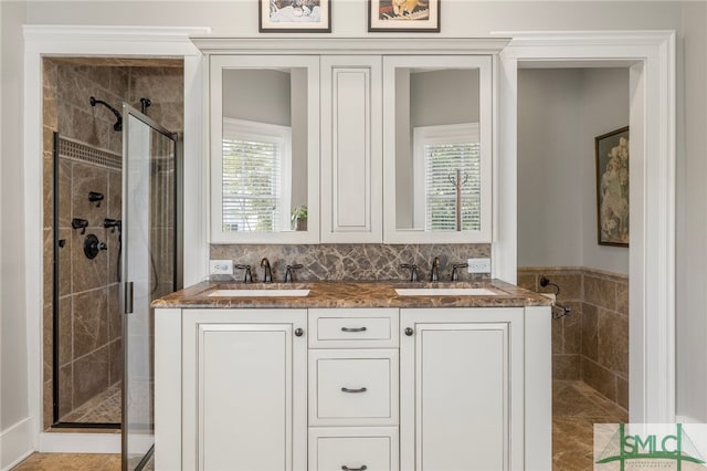 full bath featuring double vanity, a sink, and a stall shower