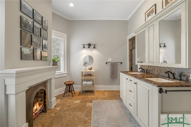 full bath with crown molding, a warm lit fireplace, stone finish flooring, and a sink