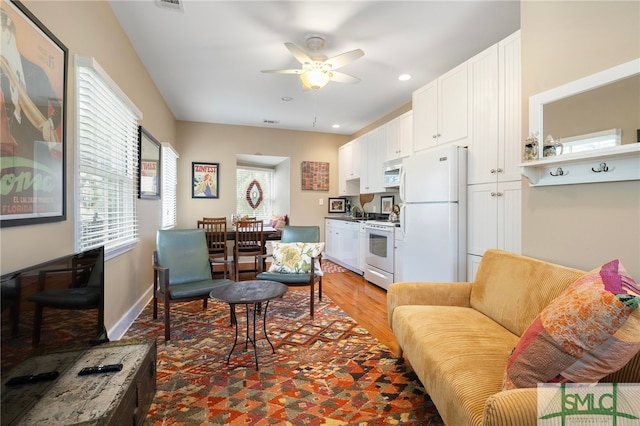 living room featuring light wood-style floors, a ceiling fan, and recessed lighting