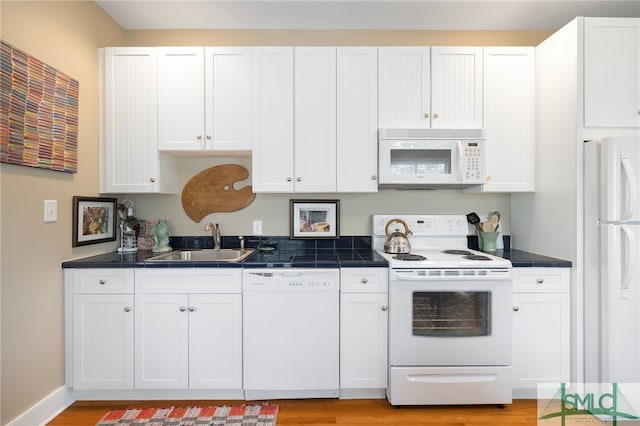 kitchen featuring a sink, white cabinetry, white appliances, and light wood-style flooring