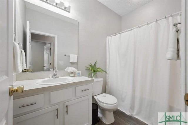bathroom with vanity, toilet, a textured ceiling, wood finished floors, and a shower with curtain