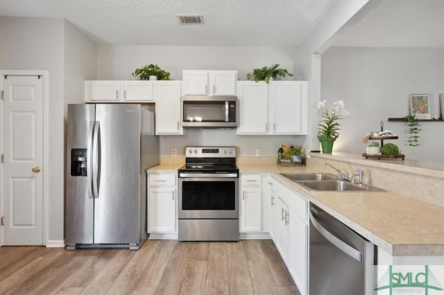 kitchen featuring a sink, light countertops, stainless steel appliances, a peninsula, and visible vents