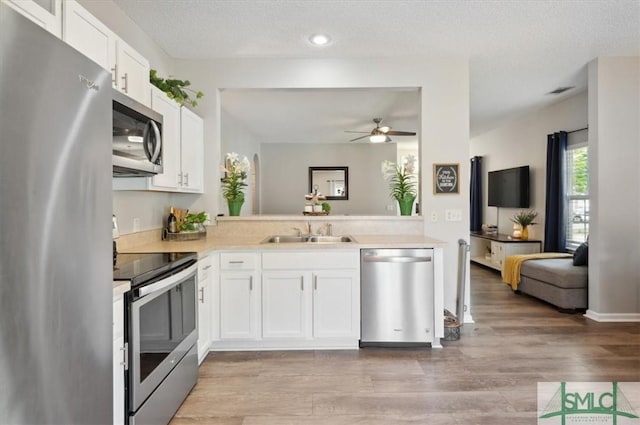kitchen featuring a sink, light countertops, stainless steel appliances, a ceiling fan, and white cabinetry