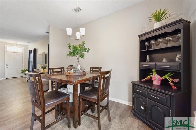 dining area featuring an inviting chandelier, baseboards, light wood finished floors, and visible vents
