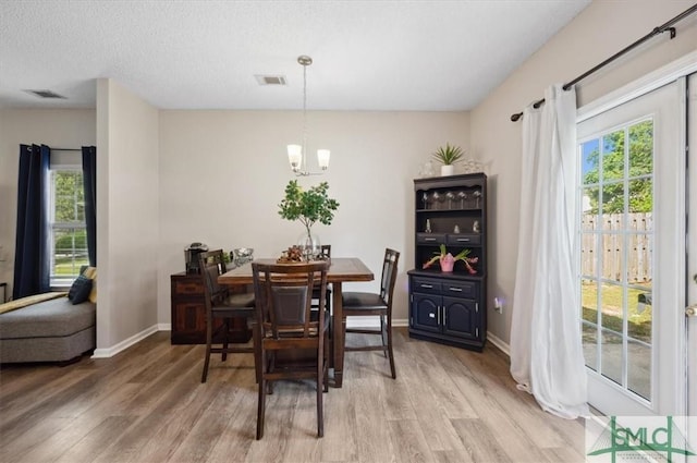 dining space with a chandelier, baseboards, visible vents, and light wood-style flooring