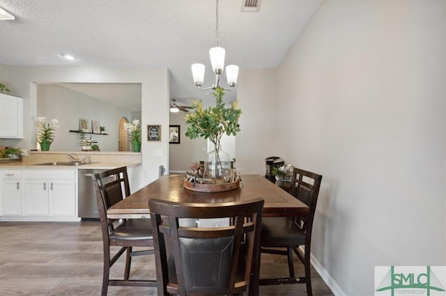 dining space featuring baseboards, visible vents, ceiling fan with notable chandelier, and light wood-style floors