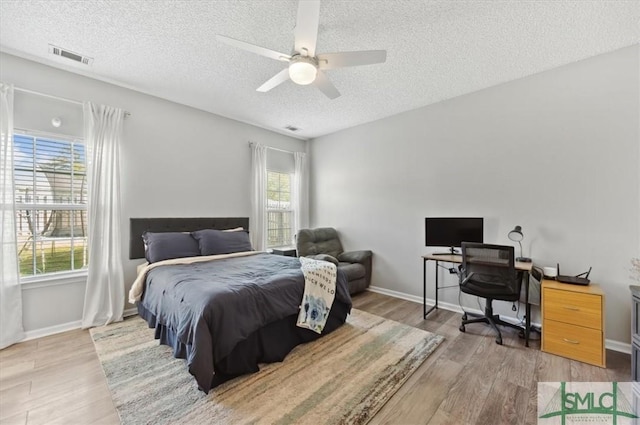 bedroom featuring light wood finished floors, a textured ceiling, and visible vents
