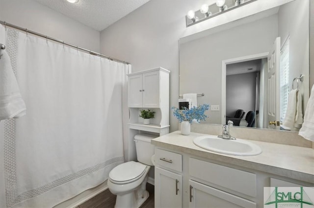 ensuite bathroom featuring vanity, wood finished floors, toilet, connected bathroom, and a textured ceiling