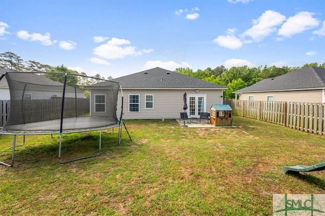 rear view of property with a fenced backyard, a trampoline, a lawn, and a patio