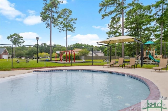 community pool featuring a lawn, fence, and playground community