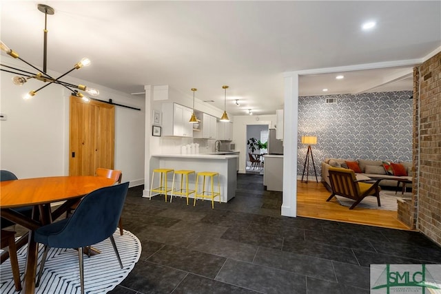 dining space with brick wall, a barn door, a notable chandelier, an accent wall, and recessed lighting