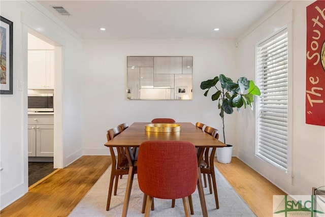 dining area featuring visible vents, ornamental molding, baseboards, light wood-type flooring, and recessed lighting