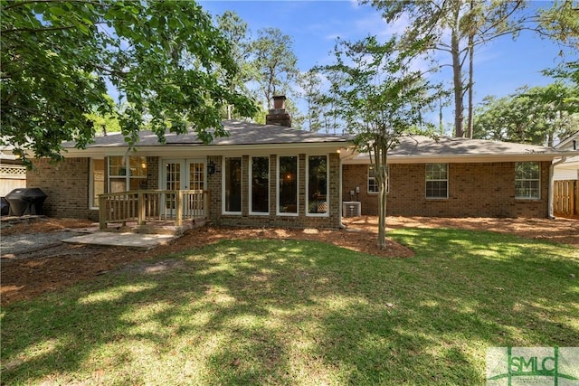 rear view of property featuring fence, a chimney, a yard, and brick siding