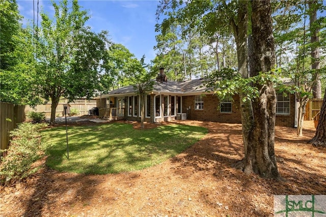 rear view of house featuring a yard, brick siding, a fenced backyard, and central air condition unit