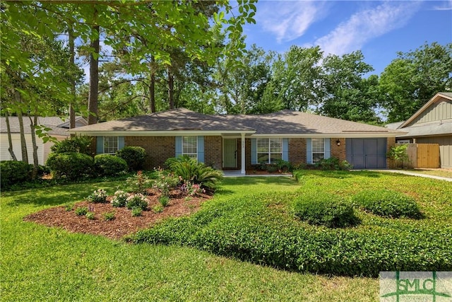 ranch-style home featuring fence, an attached garage, a front lawn, and brick siding