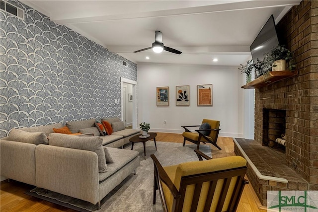 living room featuring ceiling fan, wood finished floors, a fireplace, and beamed ceiling