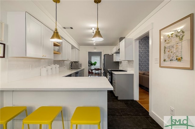 kitchen with light countertops, stainless steel gas range oven, backsplash, and visible vents