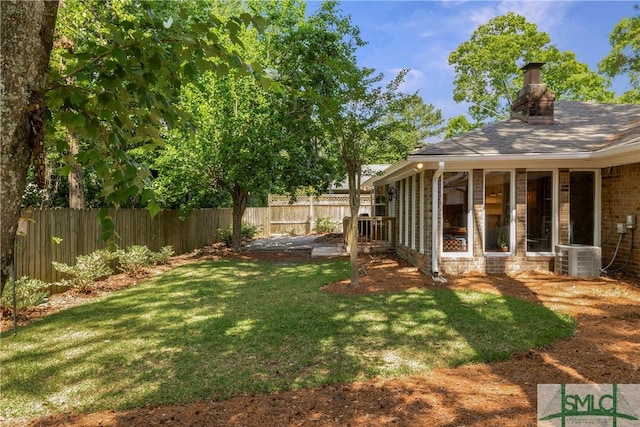view of yard featuring a sunroom, a fenced backyard, and central air condition unit
