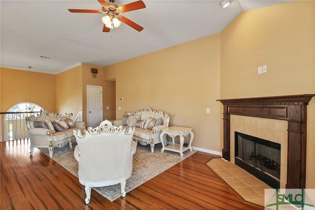 living room featuring baseboards, ceiling fan, wood finished floors, and a tile fireplace