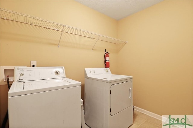 laundry room with light tile patterned floors, baseboards, laundry area, and washer and dryer