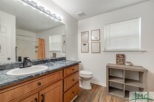 full bathroom with visible vents, wood finished floors, vanity, baseboards, and toilet