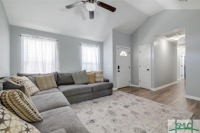 living room featuring baseboards, a ceiling fan, wood finished floors, and vaulted ceiling