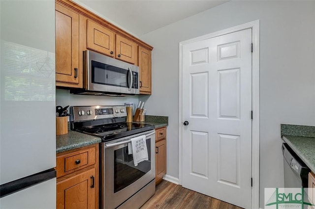 kitchen featuring brown cabinets, dark wood-style flooring, dark countertops, and appliances with stainless steel finishes