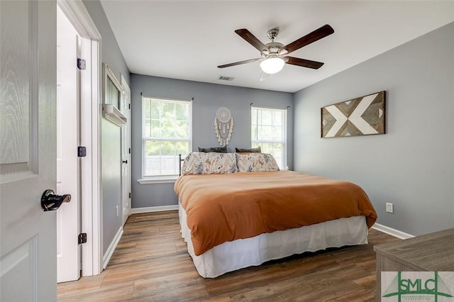 bedroom featuring baseboards, ceiling fan, wood finished floors, and visible vents
