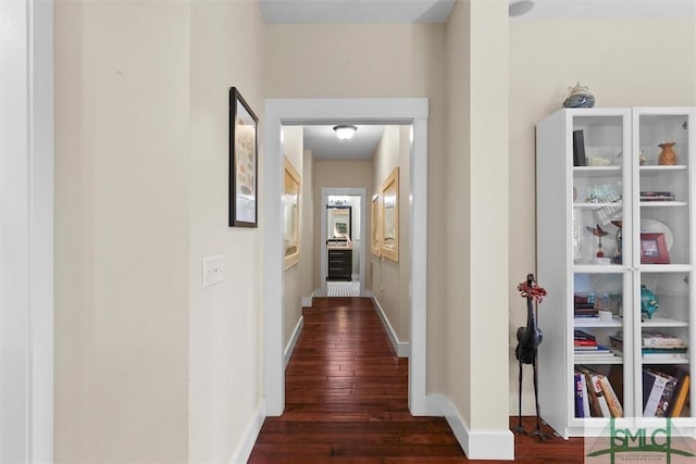 corridor with baseboards and wood finished floors