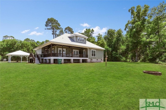 rear view of property with a lawn, a wooden deck, a gazebo, and metal roof